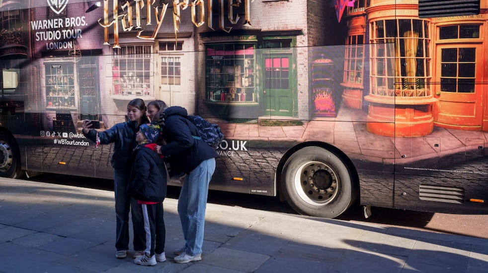Family members take their own photo alongside a Harry Potter bus ad outside St Pancras station